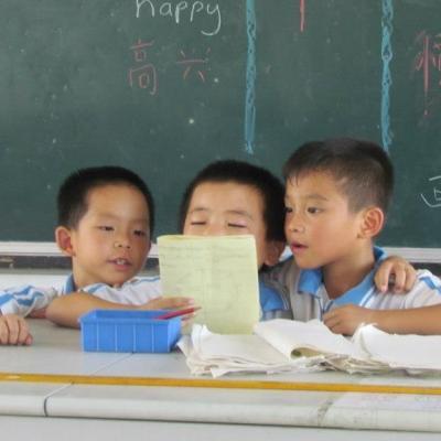 Three young boys read aloud during a class taught by a Childcare volunteer at a kindergarten in China. A Projects Abroad volunteer working with children in China listens to young boys reading aloud to improve their reading skills.